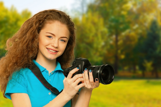 Giovane ragazza carina con fotocamera nel parco d&#39;autunno