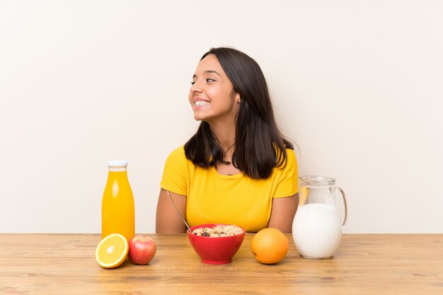 Giovane ragazza castana che mangia il latte della prima colazione che guarda al lato