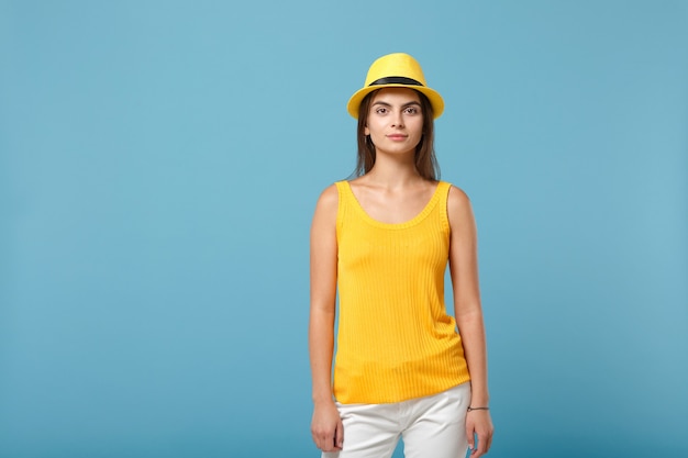 Giovane ragazza castana della donna in cappello giallo casual di estate dei vestiti che posa isolata sul ritratto blu della parete. Concetto di stile di vita di emozioni sincere della gente.