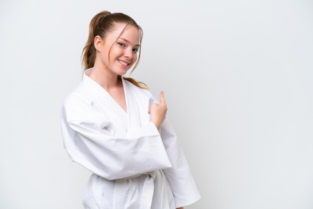 Giovane ragazza caucasica che fa karate isolato su sfondo bianco che punta indietro