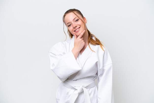 Giovane ragazza caucasica che fa karate isolato su sfondo bianco felice e sorridente