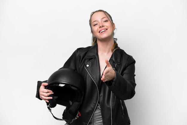 Giovane ragazza caucasica con un casco da motociclista isolato su sfondo bianco che stringe la mano per chiudere un buon affare