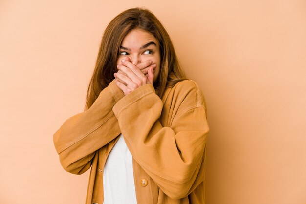 Giovane ragazza caucasica magra dell'adolescente premurosa alla ricerca di uno spazio di copia che copre la bocca con la mano.