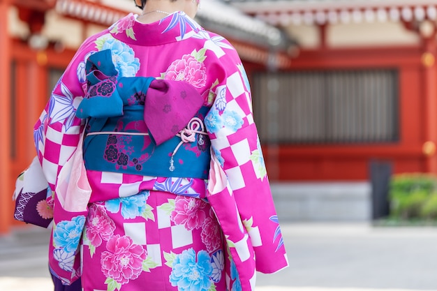 Giovane ragazza che indossa il kimono giapponese in piedi davanti al tempio Sensoji a Tokyo,