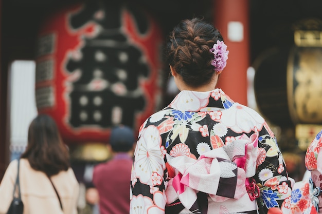 Giovane ragazza che indossa il kimono giapponese in piedi davanti al tempio Sensoji a Tokyo,