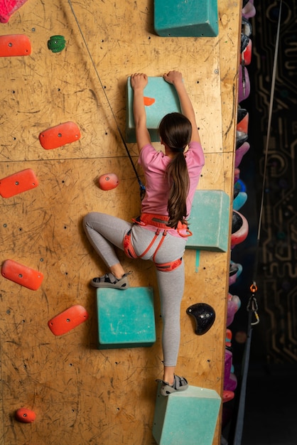 Giovane ragazza che si arrampica al chiuso nell'arena