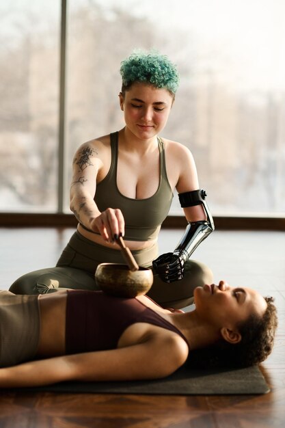 Giovane ragazza che si rilassa durante lo yoga mentre l'istruttore usa la campana tibetana