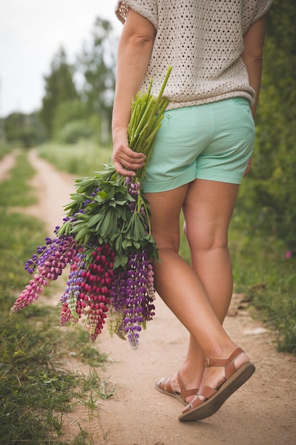 giovane ragazza che tiene tra le mani un grande mazzo di bellissimi fiori di lupino colorati