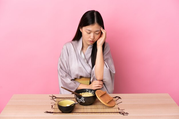 Giovane ragazza cinese che indossa il kimono e mangiare spaghetti con mal di testa