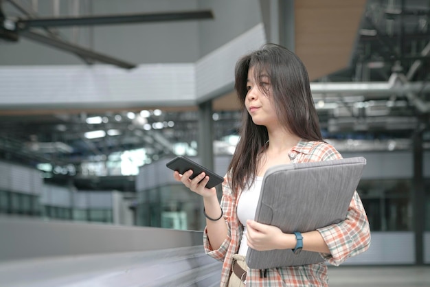 Giovane ragazza cinese che tiene una borsa per documenti e un cellulare