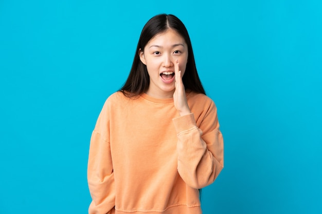 Giovane ragazza cinese sopra gridando isolato con la bocca spalancata