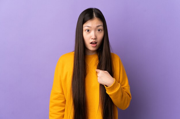 Giovane ragazza cinese sopra viola che punta a se stessi