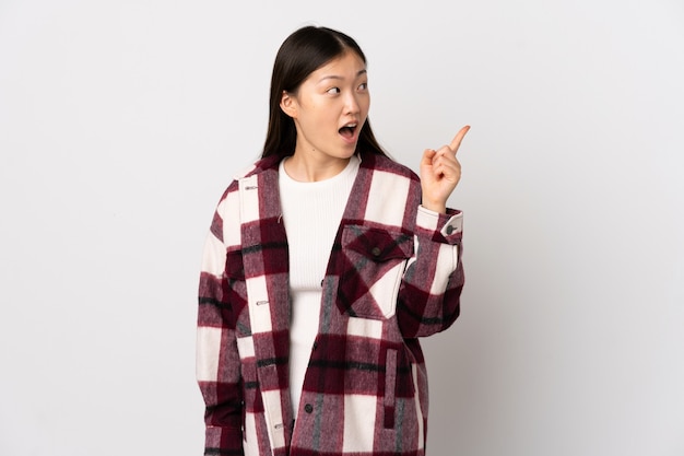 Giovane ragazza cinese su bianco isolato che intende realizzare la soluzione sollevando un dito