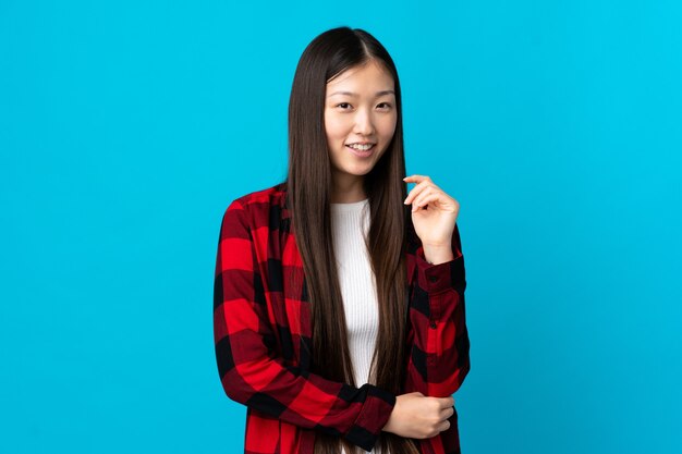Giovane ragazza cinese su sfondo blu isolato ridendo