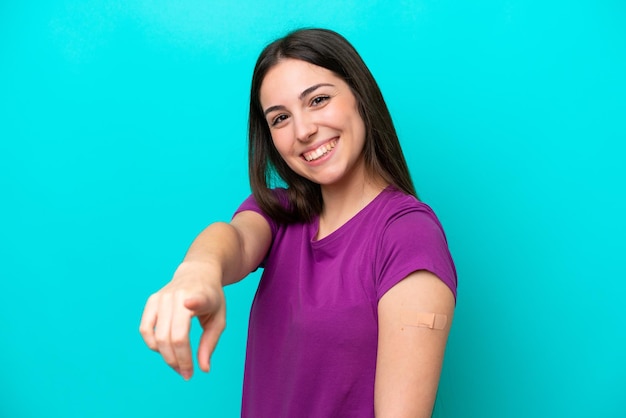 Giovane ragazza con cerotti isolati su sfondo blu punta il dito contro di te con un'espressione sicura