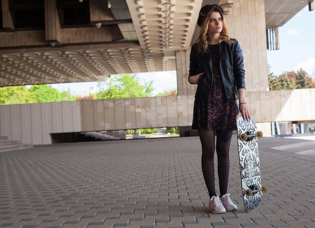 Giovane ragazza con lo skateboard con la mano in tasca