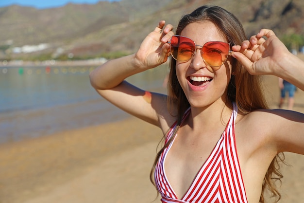 Giovane ragazza con occhiali da sole sulla spiaggia