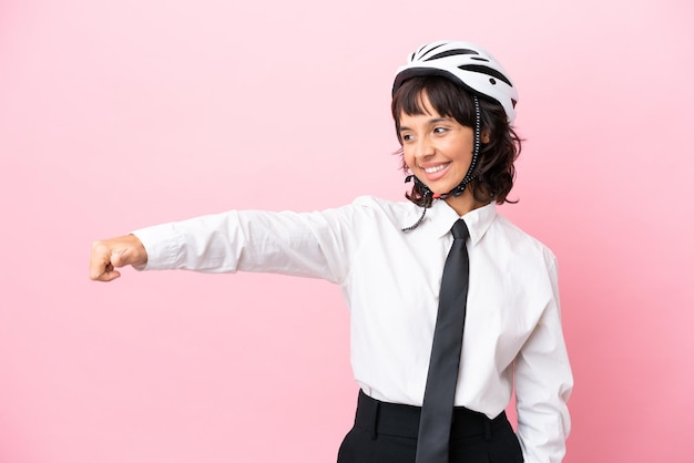 Giovane ragazza con un casco da bici isolato su sfondo rosa che dà un pollice in alto gesto