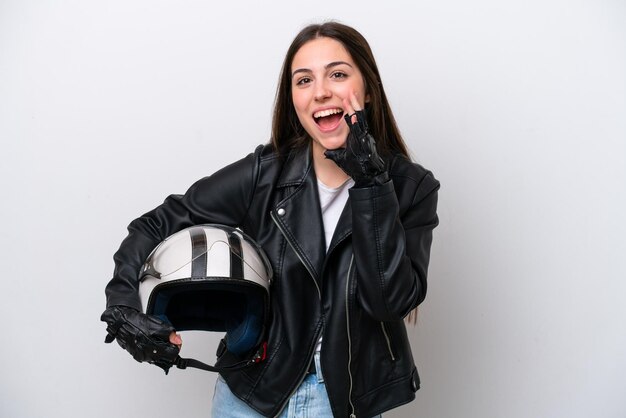 Giovane ragazza con un casco da motociclista isolato su sfondo bianco che grida con la bocca spalancata