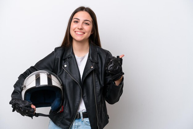 Giovane ragazza con un casco da motociclista isolato su sfondo bianco che punta di lato per presentare un prodotto