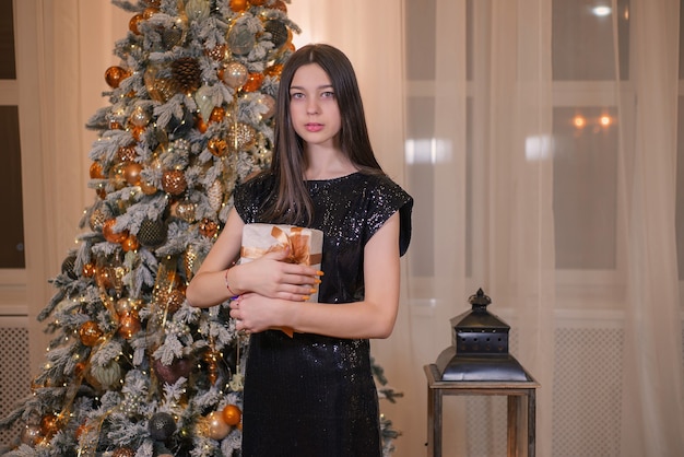 giovane ragazza con un regalo vicino all'albero di Natale a Natale