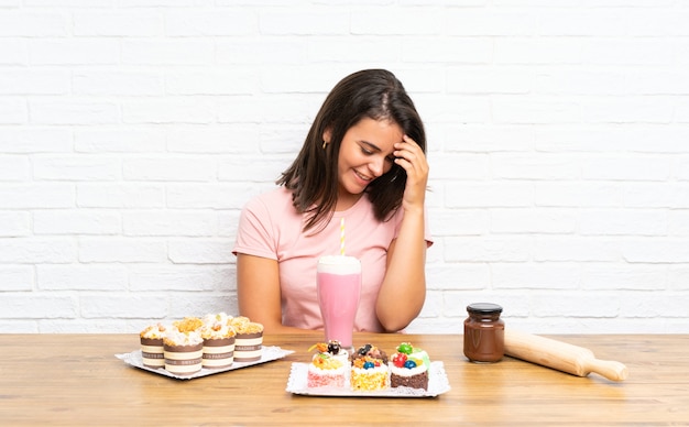 Giovane ragazza con un sacco di diverse mini torte che ridono