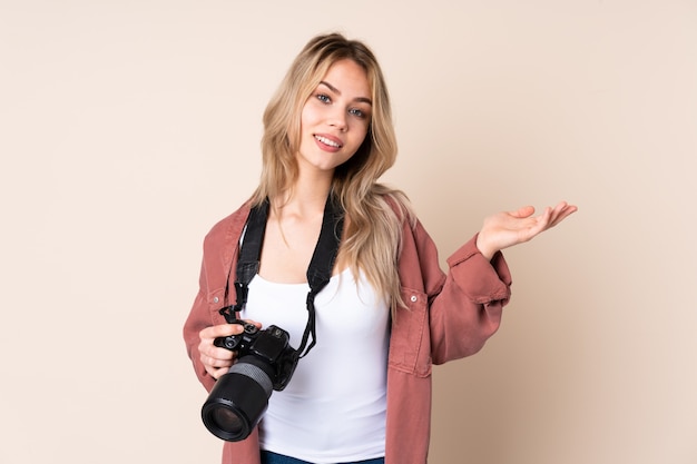 Giovane ragazza del fotografo sopra la parete che estende le mani al lato