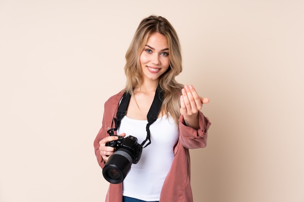 Giovane ragazza del fotografo sopra la parete che invita a venire con la mano