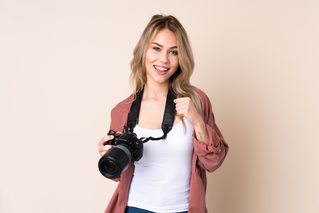 Giovane ragazza del fotografo sopra la parete isolata che celebra una vittoria