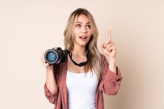 Giovane ragazza del fotografo sopra la parete isolata rivolta verso l'alto e sorpresa