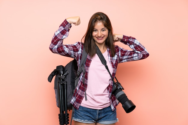 Giovane ragazza del fotografo sopra la parete rosa isolata che celebra una vittoria