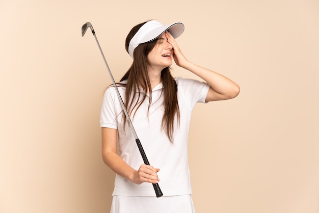 Giovane ragazza del giocatore di golf isolata sul beige che sorride molto