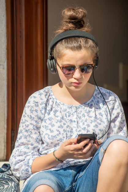 Giovane ragazza dell&#39;adolescente con musica d&#39;ascolto degli occhiali da sole all&#39;aperto