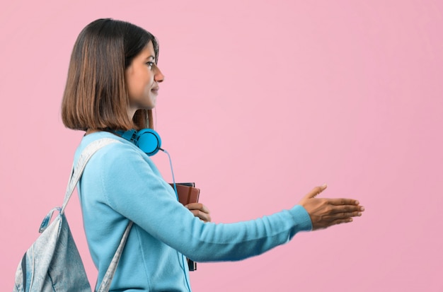 Giovane ragazza dell&#39;allievo con il handshake blu delle cuffie e del maglione dopo il buon affare