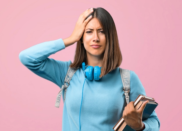 Giovane ragazza dell&#39;allievo con il maglione e le cuffie blu infelici e frustrati