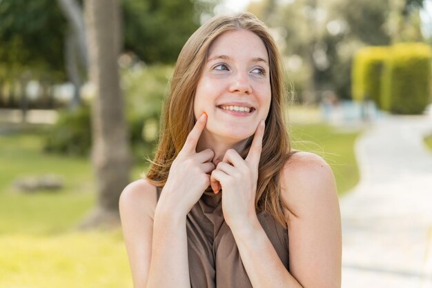 Giovane ragazza francese all'aperto sorridendo con un'espressione felice e piacevole