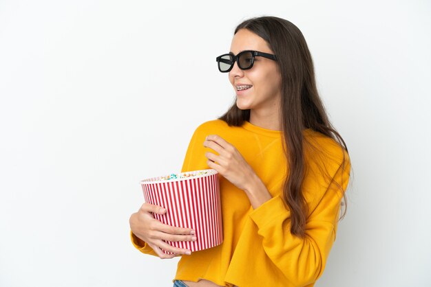 Giovane ragazza francese isolata su sfondo bianco con occhiali 3d e con in mano un grande secchio di popcorn