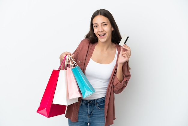 Giovane ragazza francese isolata su sfondo bianco tenendo le borse della spesa e una carta di credito