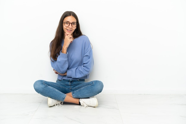 Giovane ragazza francese seduta sul pavimento con gli occhiali e sorridente