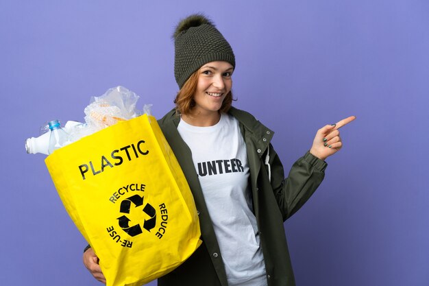 Giovane ragazza georgiana che tiene una borsa piena di bottiglie di plastica da riciclare che punta indietro