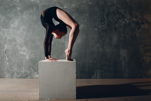 Giovane ragazza ginnasta professionista donna danza ginnastica ritmica con cubo bianco in studio