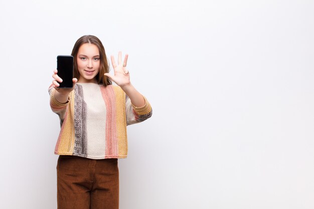 Giovane ragazza graziosa bionda che tiene uno smartphone