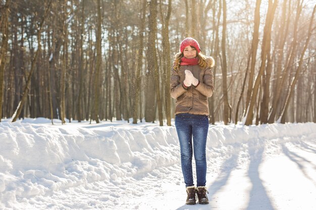 Giovane ragazza graziosa che tiene la neve in guanti.