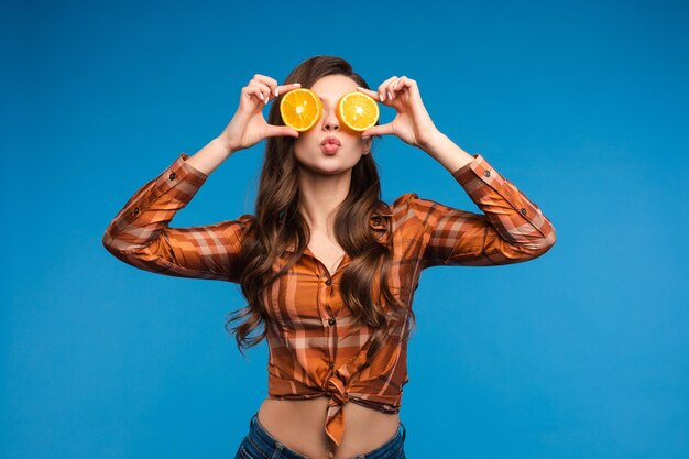 Giovane ragazza in abiti casual che nasconde il viso dietro i frutti