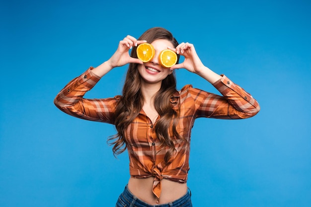 Giovane ragazza in abiti casual che nasconde il viso dietro i frutti