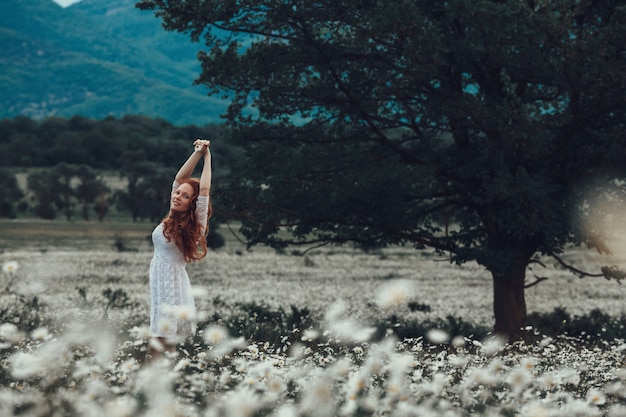 giovane ragazza in abito bianco nel campo di camomilla