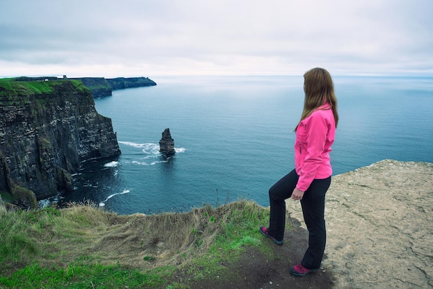 Giovane ragazza in piedi presso le scogliere di Moher