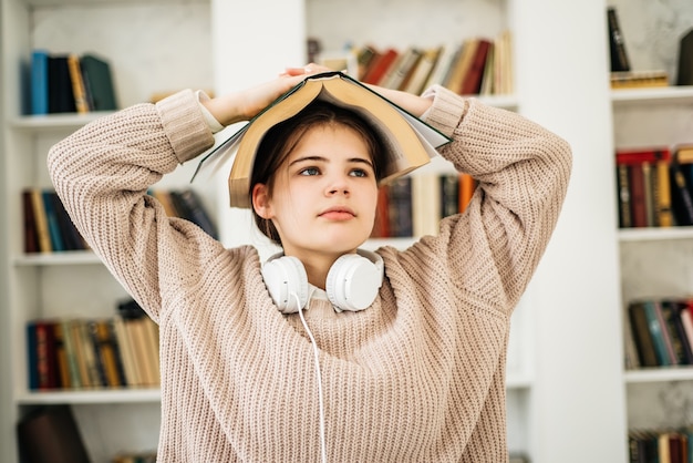 Giovane ragazza in piedi vicino allo scaffale in biblioteca