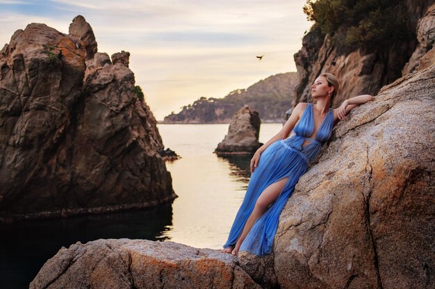 Giovane ragazza in posa in abito blu sulla costa