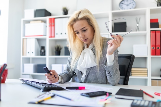 Giovane ragazza in ufficio a lavorare con un pennarello e documenti.